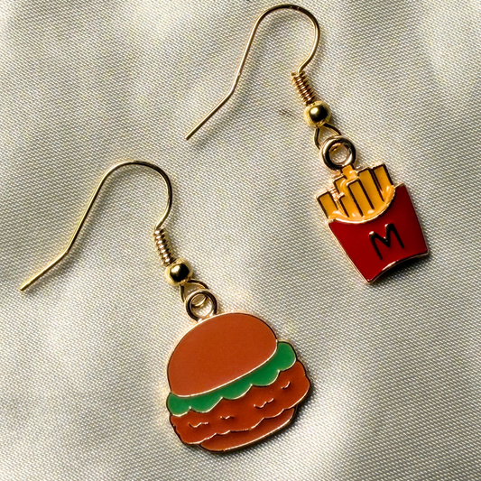 Hamburger and french fry earrings on a reflective surface
