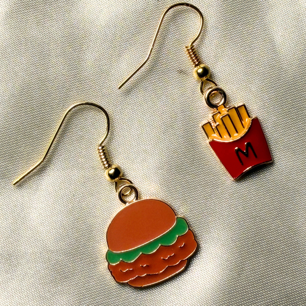 Hamburger and french fry earrings on a reflective surface